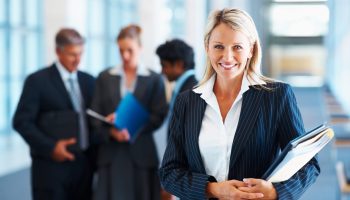 Happy businesswoman with colleagues in the background